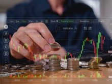 A man is lifting stacks of coins with investment information superimposed overtop of the image.