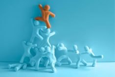 A graphic showing a group of human-shaped, light green "people" grouping together to boost an an orange-cloured figure higher up a wall.