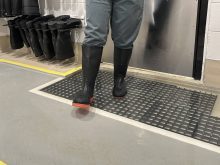 A person visible only from the waist down steps out of a "boot dip" designed to halt the spread of pathogens.