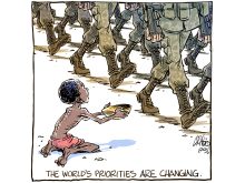 An editorial cartoon showing a child on his knees holding an empty bowl out as just the legs and boots of soldiers are visible as they march by.