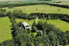 An aerial view of a lush green farmyard surrounded by trees.