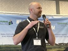A man with stands on a stage speaking into a microphone at the Farming Smarter Conference and Trade Show in Lethbridge.