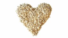 A pile of rolled oats in the shape of a heart on a white background.