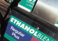 A close up of a white, green and blue sign on a gas pump that reads, "Ethanol Blend Regular Plus."