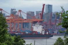 A container ship is docked in the Port of Vancouver on a cloudy day.