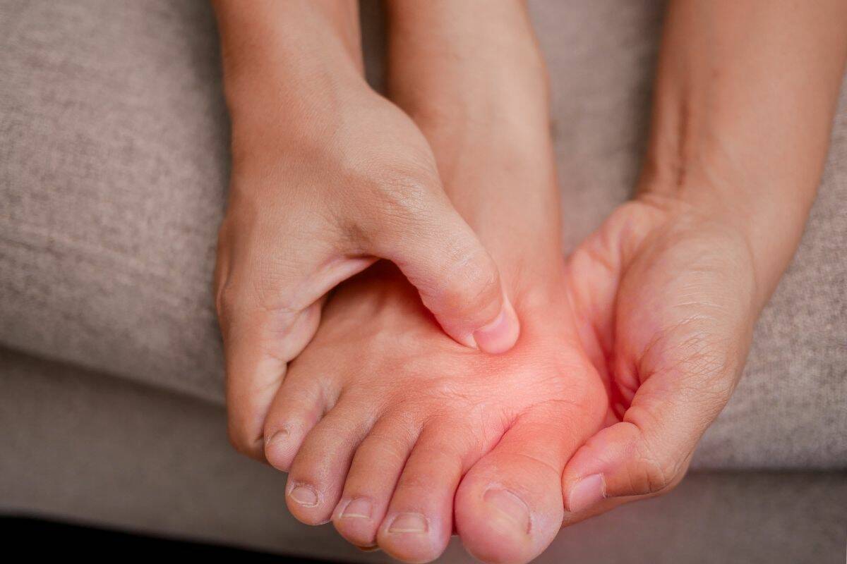 Hands rubbing a sore big toe joint.