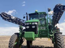 The booms of a high-clearance sprayer are folded by its side with a SWAT Cam visible on each boom.