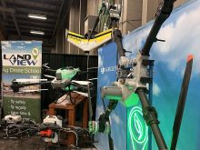 A number of drones are on display in a booth at at trade show.