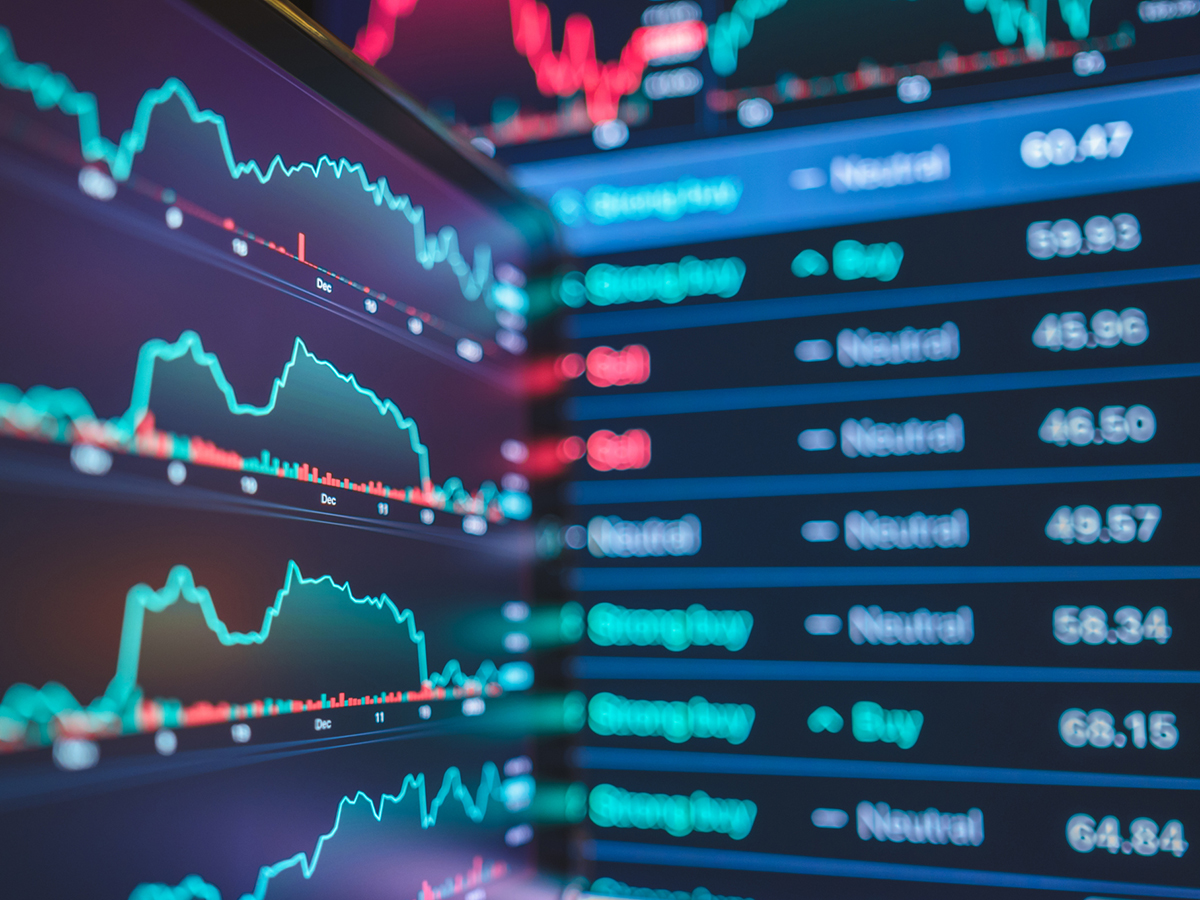 Non-descript market and financial charts displayed on screens.