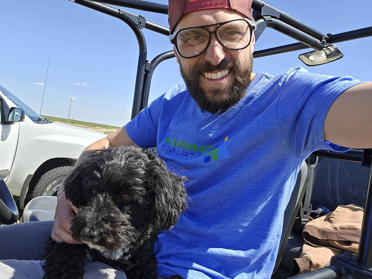 Mike Gretzinger of Farming Smarter takes a selfie of him and his dog seated in a side-by-side under a clear blue sky.